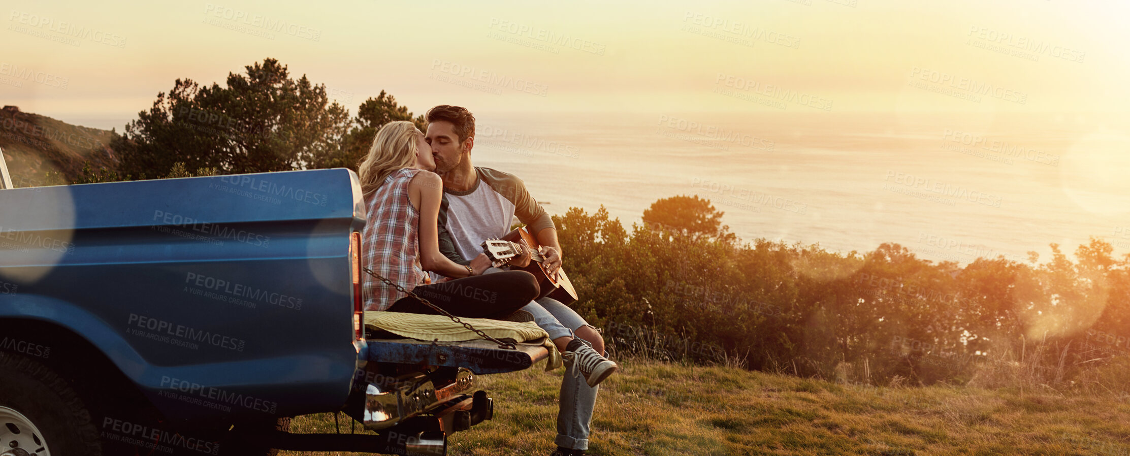 Buy stock photo Kiss, nature and couple by car for travel by sunset on vacation, weekend or holiday. Happy, love and young man and woman outdoor in field by vehicle for road trip getaway together in evening.