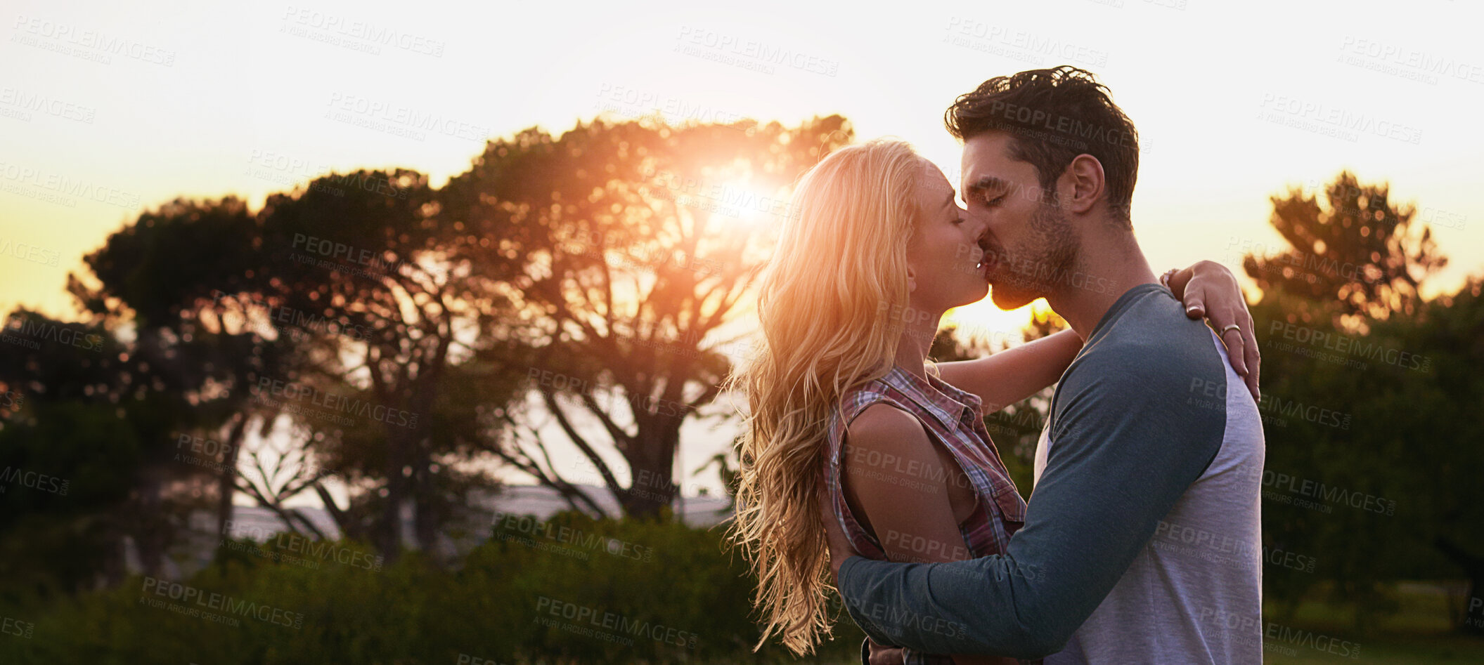 Buy stock photo Couple, kiss or sunset with hug in nature for romance, love or affection in forest or woods. Man, woman or lovers with intimacy, trees or sunshine on banner for romantic date, bonding or relationship