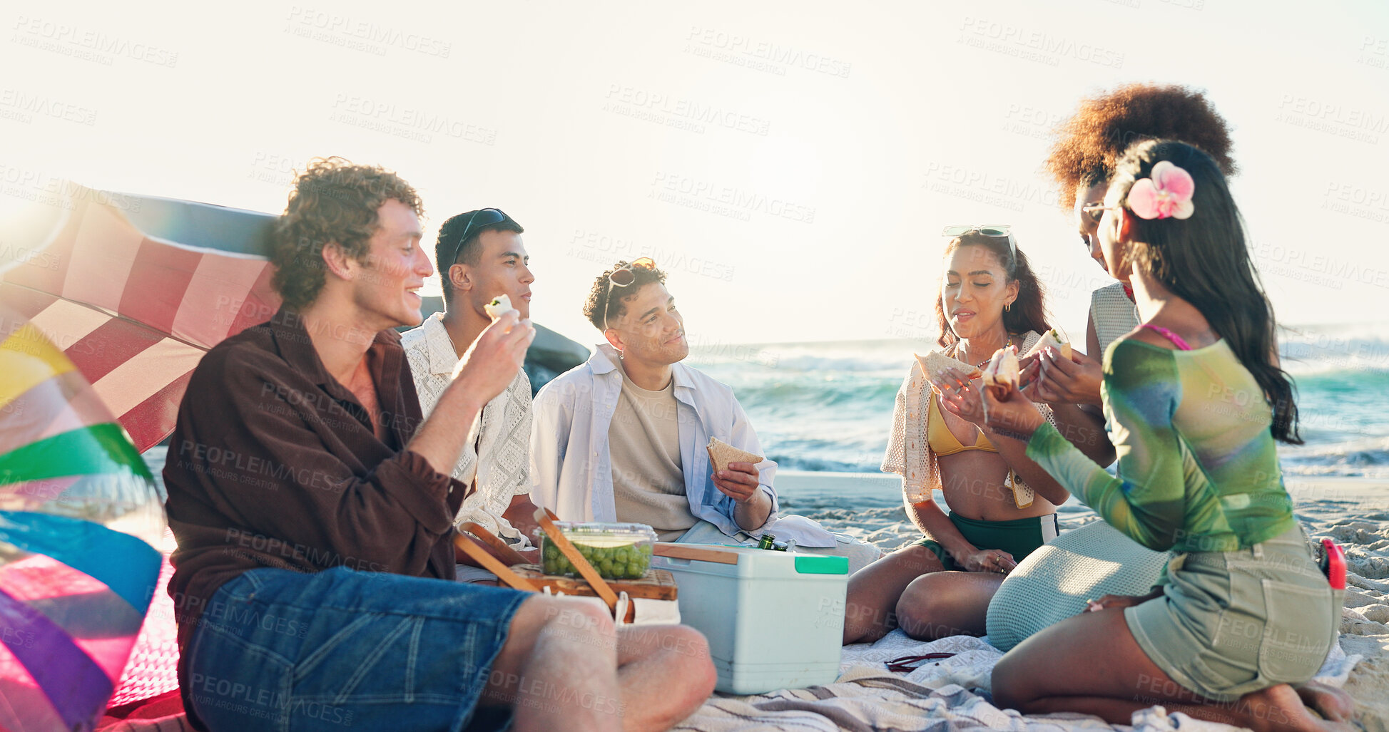 Buy stock photo Beach, picnic and group of people with food, sandwich and eating together on tropical holiday celebration. Friends, men and women relax at ocean with lunch, fun outdoor adventure and happy vacation