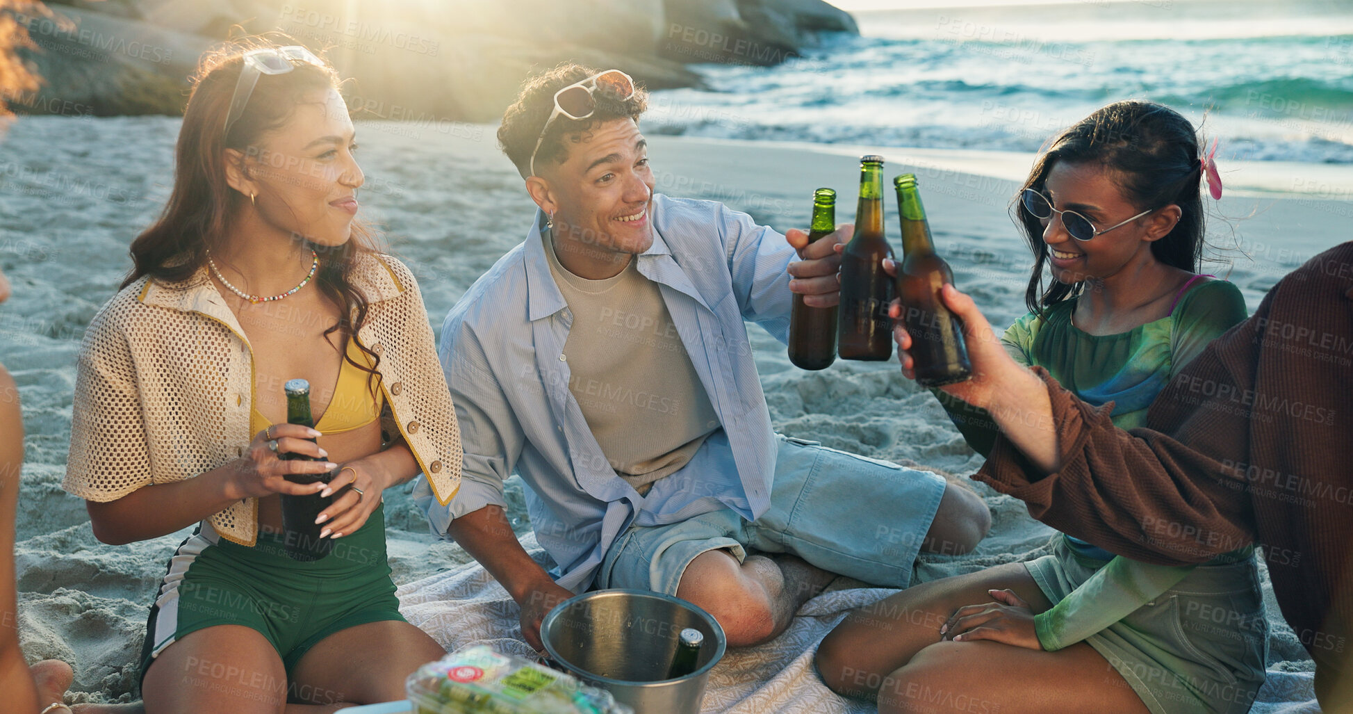 Buy stock photo Beach, cheers and group of happy people with beer, smile or bonding on tropical holiday together. Friends, men and women toast at ocean with drinks, fun outdoor adventure or sunset picnic celebration