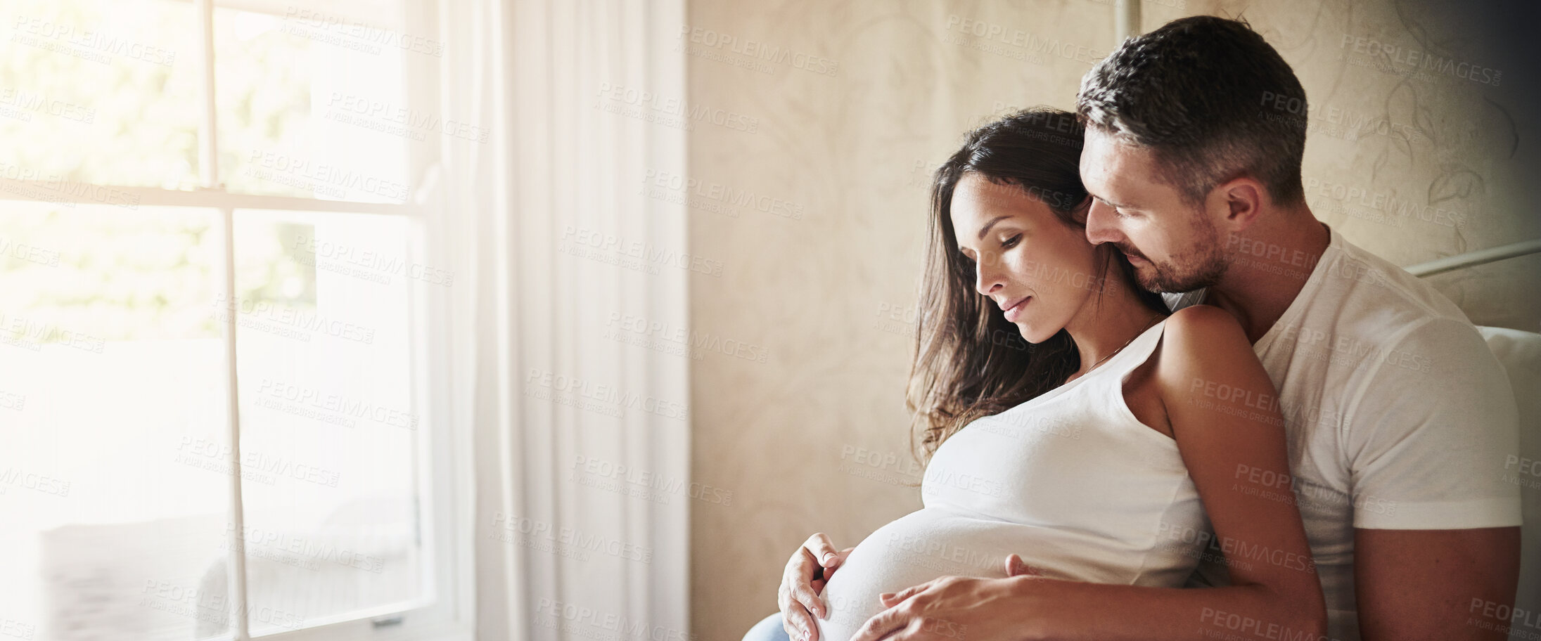 Buy stock photo Relax, pregnancy and couple by window in home with love, bonding and marriage commitment to family. Rest, maternity leave and man embracing pregnant woman for prenatal care connection in apartment.