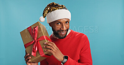 Buy stock photo Portrait, black man and gift for Christmas in studio of festive celebration, surprise present and Santa Claus. Smile, male person and box for giveaway announcement, holiday reward and blue background