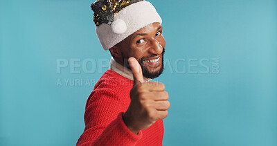 Buy stock photo Christmas, man and portrait with thumbs up in studio for holiday promotion, festive agreement and excited. Mockup space, black person or yes gesture on blue background for good news or party approval