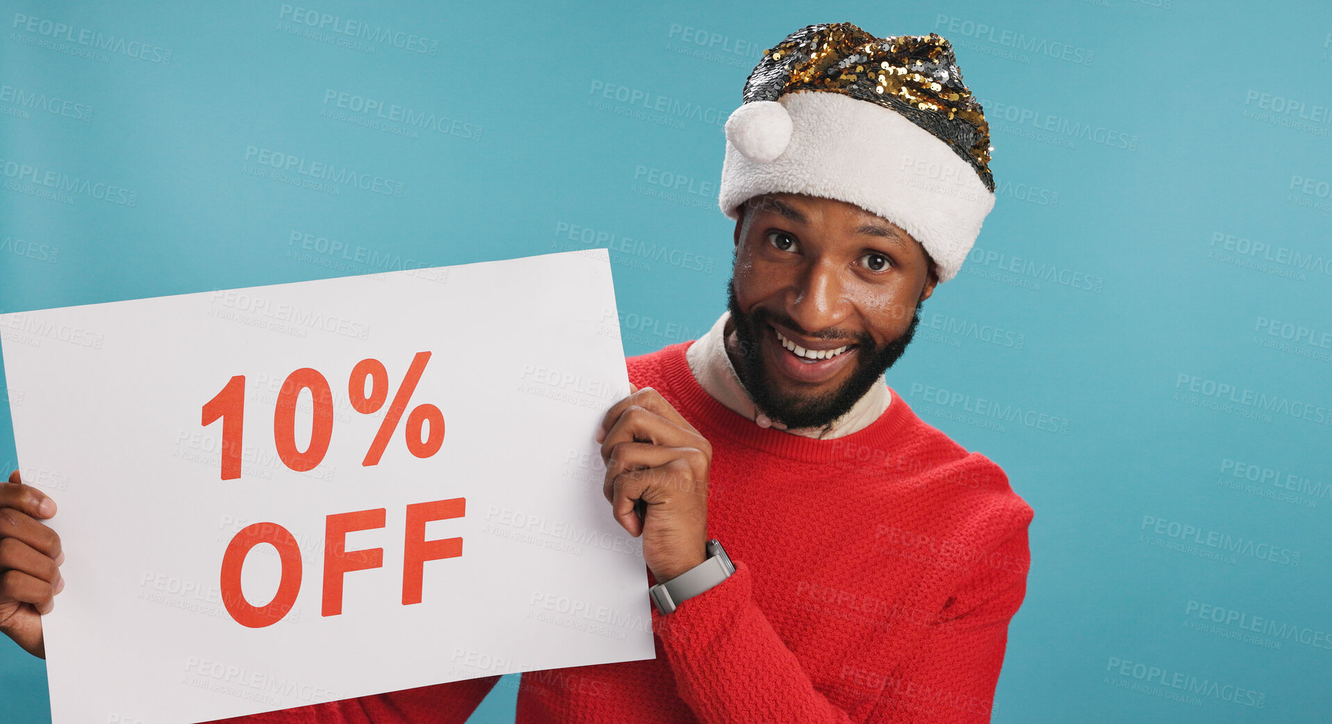 Buy stock photo Board, happy and black man for christmas discount in studio with advertisement for promotion. Excited, poster and African male person with sign for deal with holiday shopping by blue background.