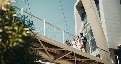 Buy stock photo Friends, students and bridge at university, walk and outdoor with low angle, talking and education at campus. Man, women and conversation with discussion, smile and diversity for learning at college