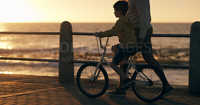 Buy stock photo Parent, child and bicycle at beach, promenade and with teaching, support and happy on vacation. Person, boy and bike with learning, adventure and play in summer with bonding by ocean in New Zealand