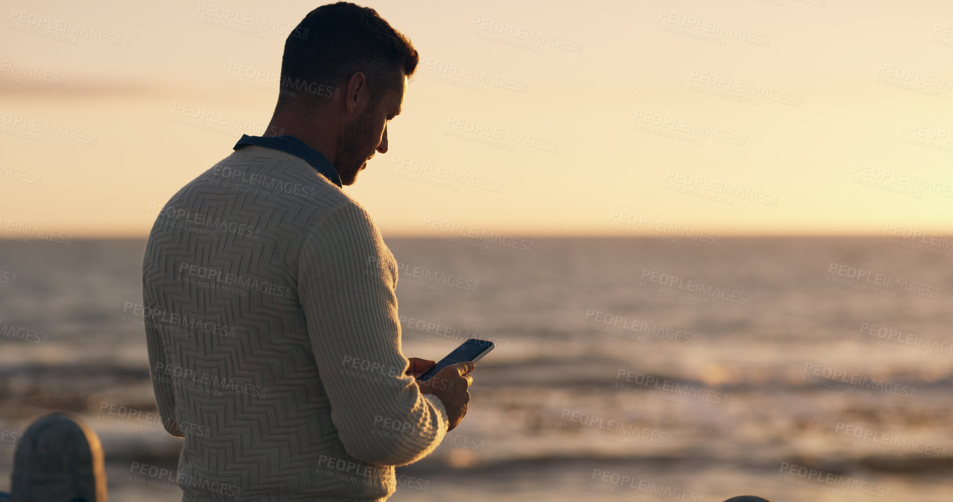Buy stock photo Man, beach and phone for texting at sunset on promenade with memory, vacation and back with web in summer. Person, smartphone and scroll on holiday with mobile app for social network in Australia