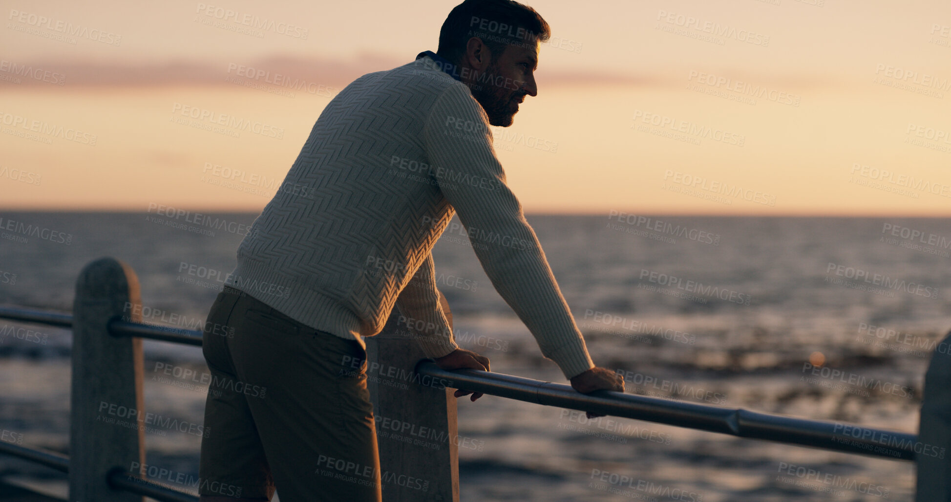 Buy stock photo Man, thinking and reflection by sea, sunset or promenade in summer with decision in evening on break. Person, pier and inspiration by ocean, beach or outdoor with sky, railing and dusk in New Zealand