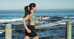 Fitness, woman and running at ocean for exercise, wellness and cardio training with fresh air. Girl, runner and challenge at seaside for training, healthy body and lose weight with endurance in Spain