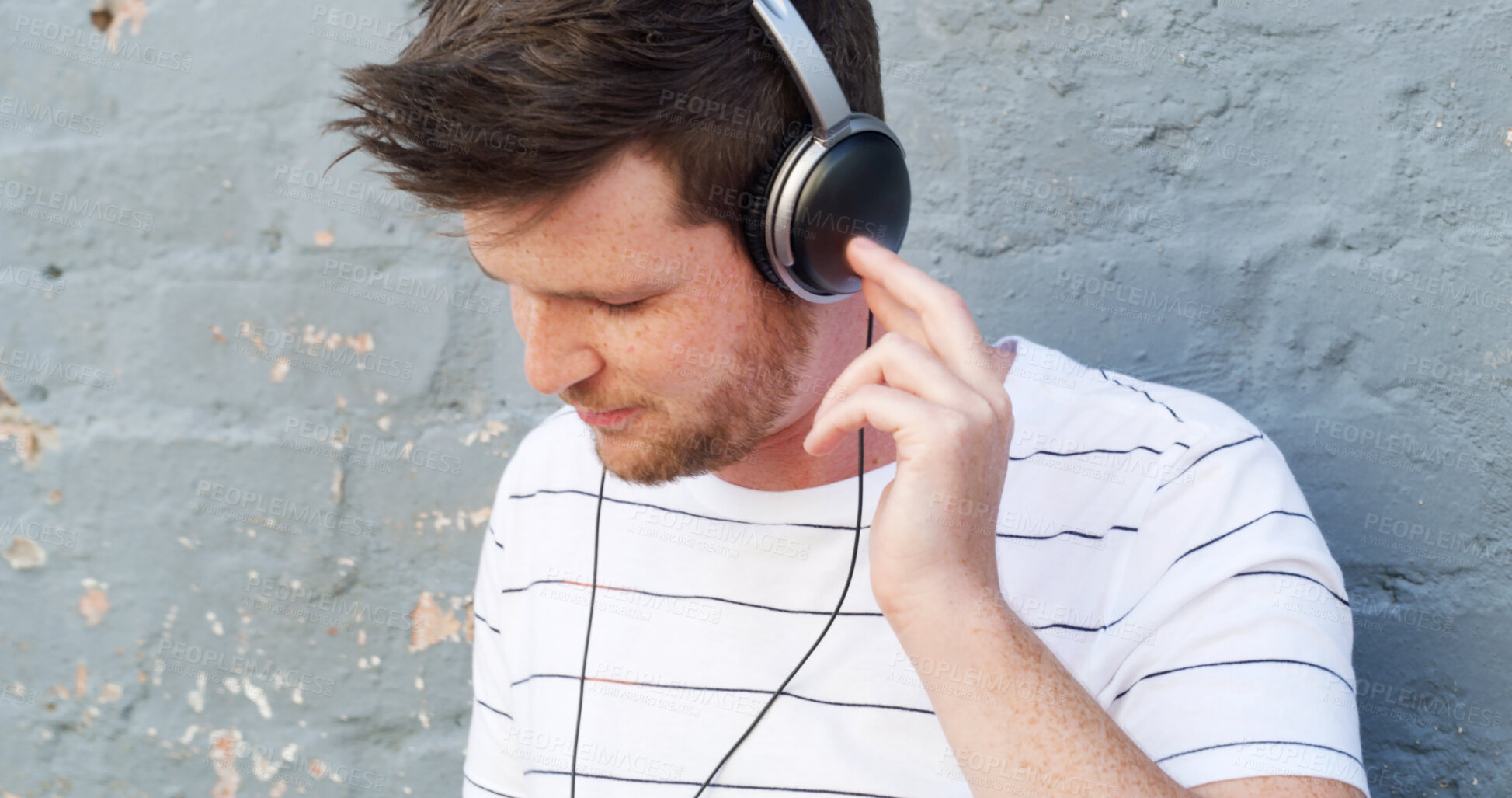 Buy stock photo Headphones, relax and man by wall for music or streaming playlist and online radio on gray background. Listening, outdoor and male person in city for learning language on podcast with audio sound