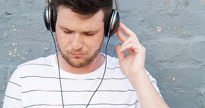 Buy stock photo Headphones, outdoor and man by wall for music, streaming zen playlist and radio on gray background. Relax, calm and male person in city for listening to binaural beats on podcast with audio sound