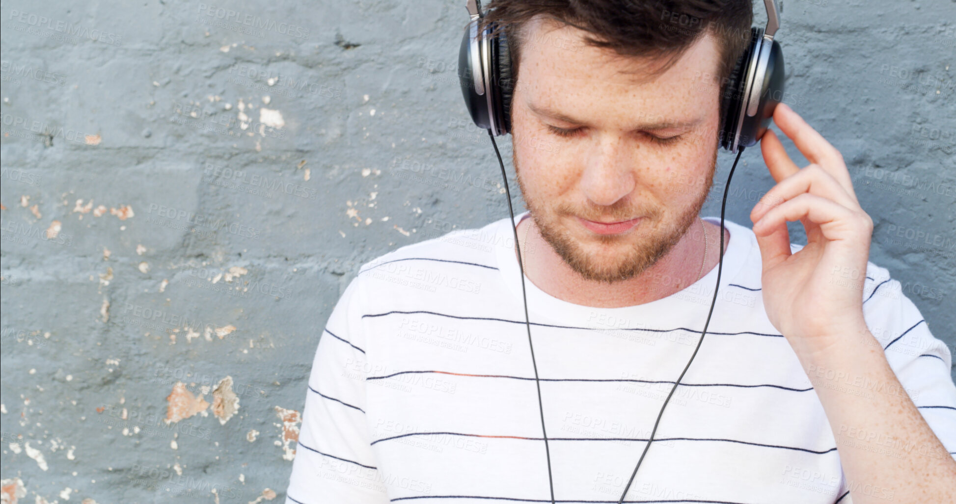 Buy stock photo Headphones, space and man by wall for music, streaming playlist and radio on gray background. Relax, outdoor and male person in city for learning language or listening to podcast with audio sound