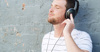 Buy stock photo Headphones, outdoor and calm man by wall for music, streaming zen playlist or radio on gray background. Relax, chill or person in city for listening to binaural beats on podcast space or audio sound