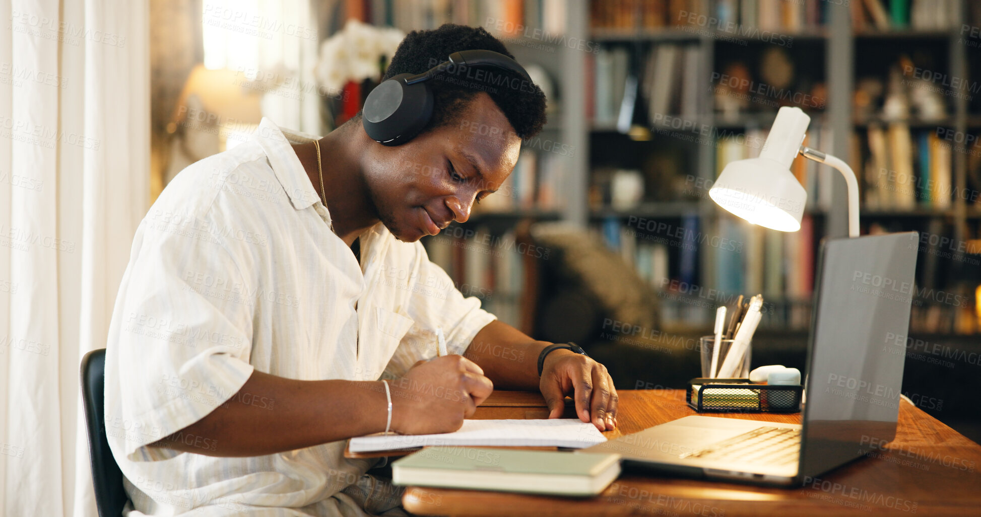 Buy stock photo Black man, headphones and writing with studying, home and happy for distance learning, development or research. Person, notes and books with music, education and online course with college project