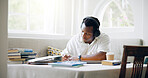 African man, student and headphones in home with books, writing or learning with listening to music with scholarship. Person, notes and streaming with studying, education or planning for college exam