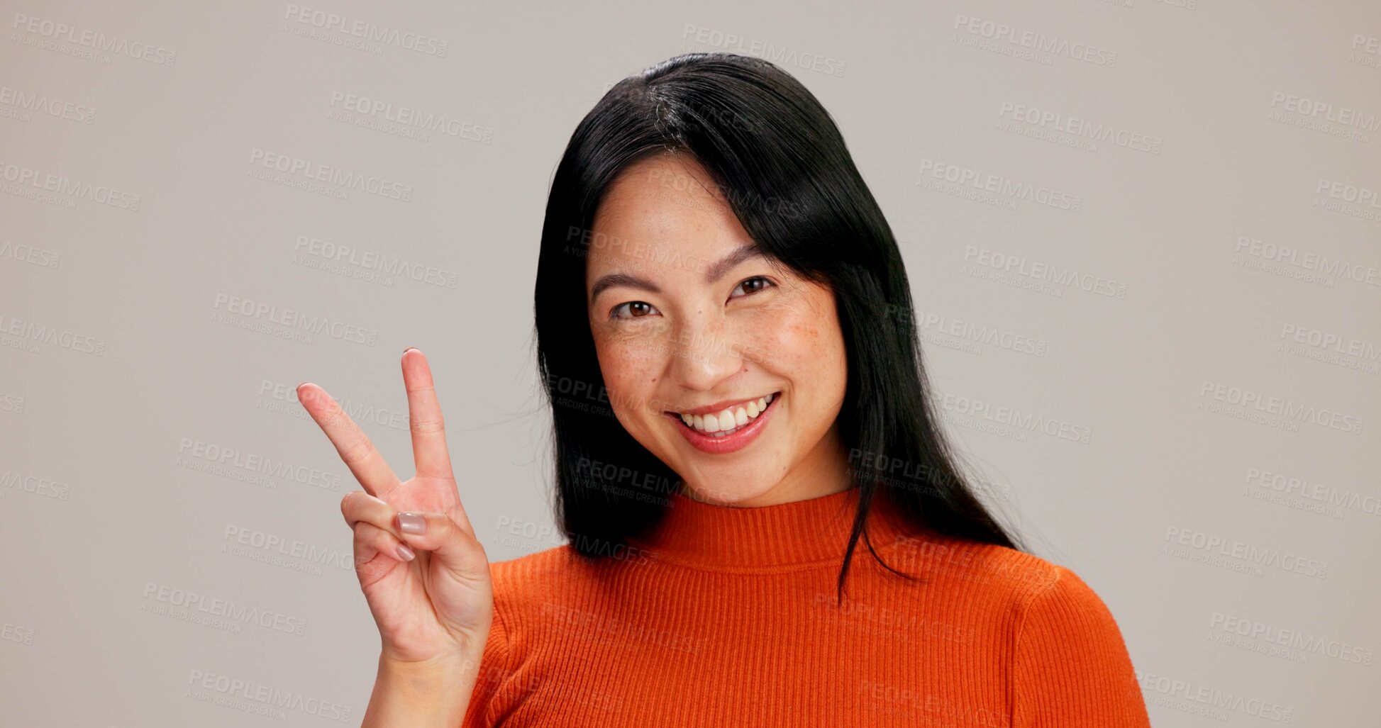 Buy stock photo Happy, asian woman and portrait with peace sign for expression or emotion on a gray studio background. Face, female person or model with smile, finger emoji or V gesture for review, opinion or symbol