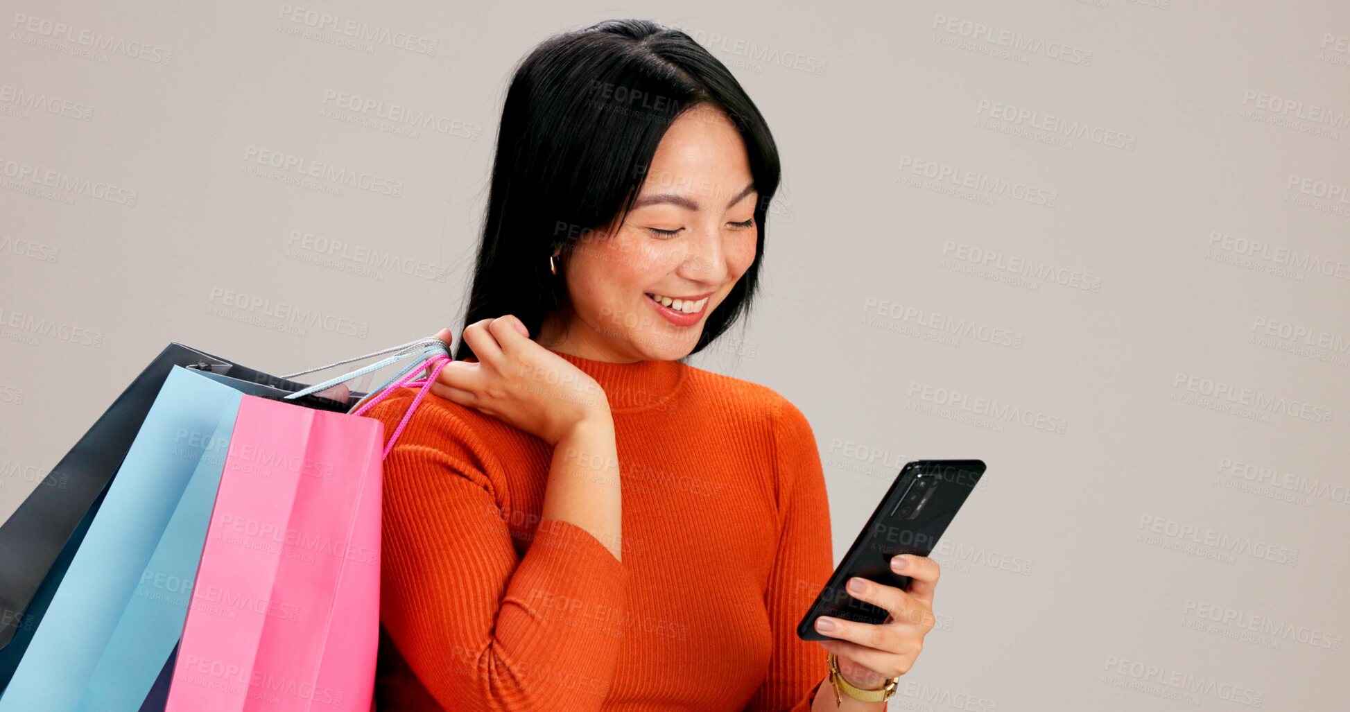 Buy stock photo Asian woman, smartphone and shopping bag in studio, smile and search for deal with e commerce by background. Girl, person and happy with phone for discount, promotion and excited with mobile app