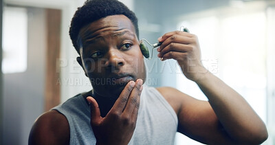 Buy stock photo Black man, jade roller and face with skincare for dermatology, facial or anti aging treatment at home. African, male person and beauty tool for hygiene, cosmetics or skin routine in bathroom at house