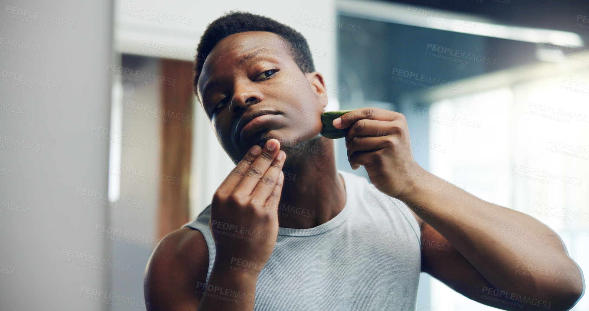 Buy stock photo Black man, gua sha and facial with skincare for dermatology or anti aging treatment at home. African, male person and face with beauty tool for hygiene, cosmetics or skin routine in bathroom at house