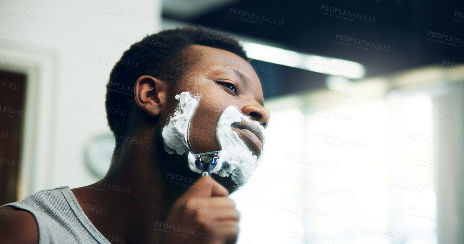 Buy stock photo Black man, shave and razor with face cream for grooming, epilation or hair removal in bathroom at home. African, male person or facial with blade, aftershave creme or clean beard for skincare routine