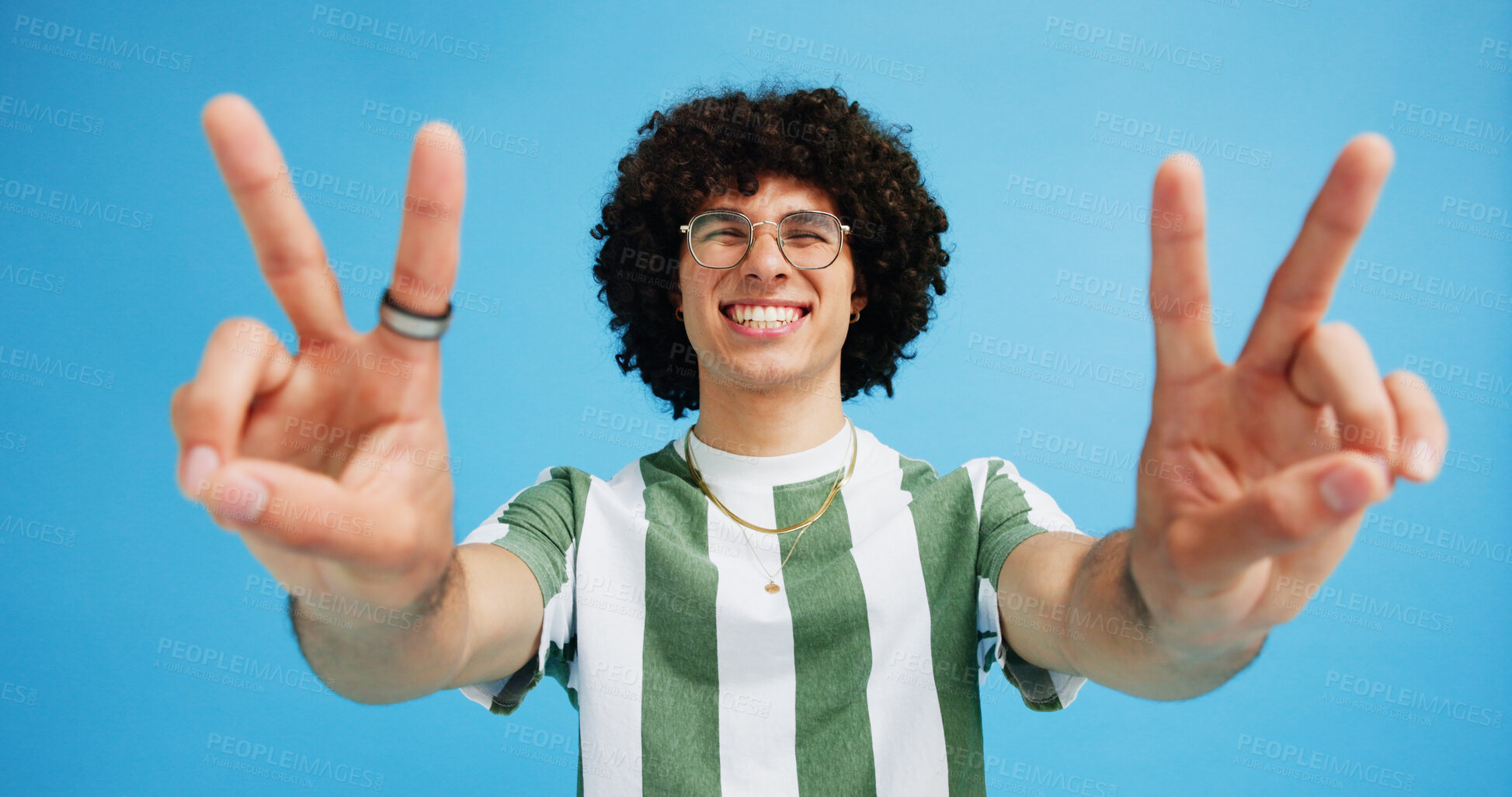 Buy stock photo Happy man, portrait and fashion with peace sign for casual style on a blue studio background. Male person, hipster or young model with smile, emoji or finger gesture for V symbol, icon or signal