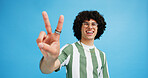 Happy man, portrait and fashion with peace sign for review, vote or expression on a blue studio background. Male person, hipster or model with smile, emoji or finger gesture for V symbol or icon