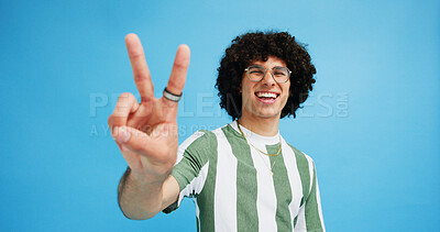 Buy stock photo Happy man, portrait and fashion with peace sign for review, vote or expression on a blue studio background. Male person, hipster or model with smile, emoji or finger gesture for V symbol or icon