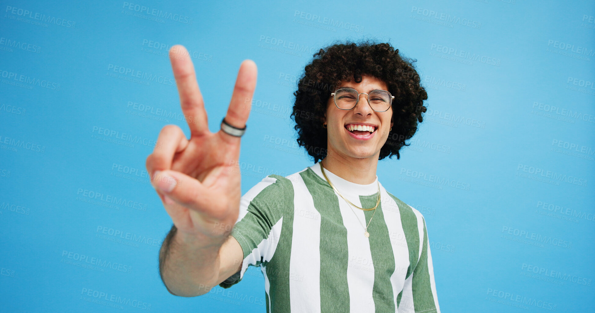 Buy stock photo Happy man, portrait and fashion with peace sign for review, vote or expression on a blue studio background. Male person, hipster or model with smile, emoji or finger gesture for V symbol or icon