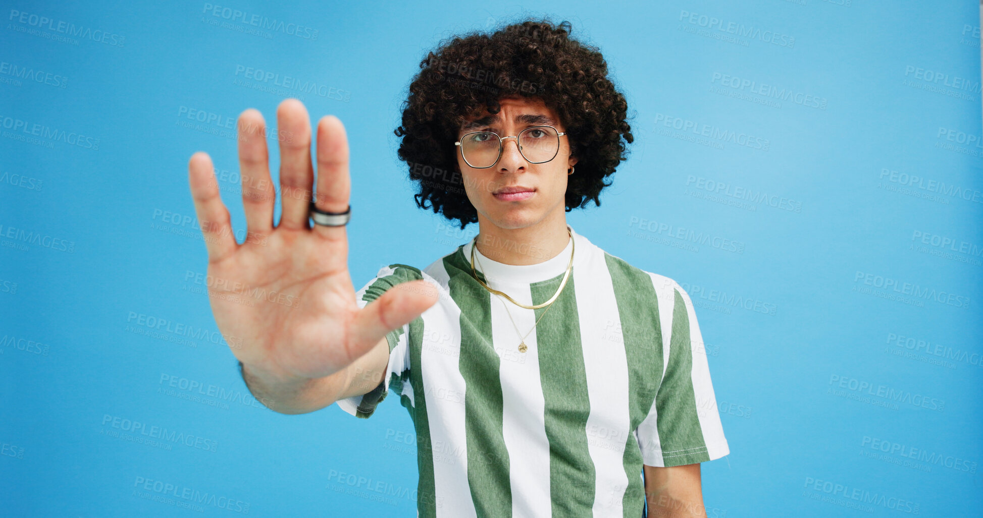 Buy stock photo Man, portrait and hand with stop for rejection, no or protest on a blue studio background. Male person, gen z or young model with gesture, sign or objection for refusal, enough or resistance on space