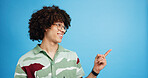 Pointing, smile and excited man with opinion, announcement and advertising in studio. Blue background, promotion and happy person with hand gesture, confidence and information in mockup space
