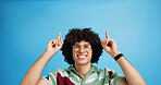 Pointing up, portrait and man with opinion, announcement and advertising smile in studio. Blue background, brand promotion and person with hand gesture, confidence and information in mockup space