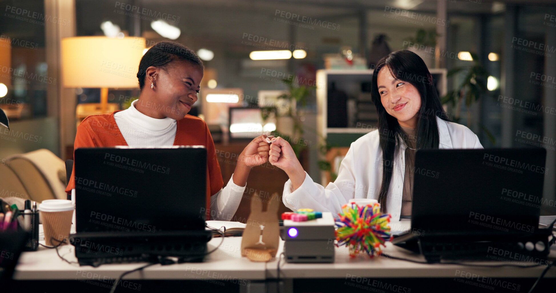 Buy stock photo Business women, night and fist bump with success for teamwork, congratulations or thank you at office. Creative, female people or colleagues working late with smile for good job, well done or winning