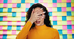 Scared, woman and face with colorful background for horror, rumor or nervous expression in studio. Terrified, female person or model covering eyes in terror, fear or afraid for peek, watch or sight