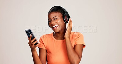 Buy stock photo Smartphone, woman and laughing with headphones on studio background for funny audio, radio app and podcast. Music playlist, black person and happy with streaming song, online sound and mockup space