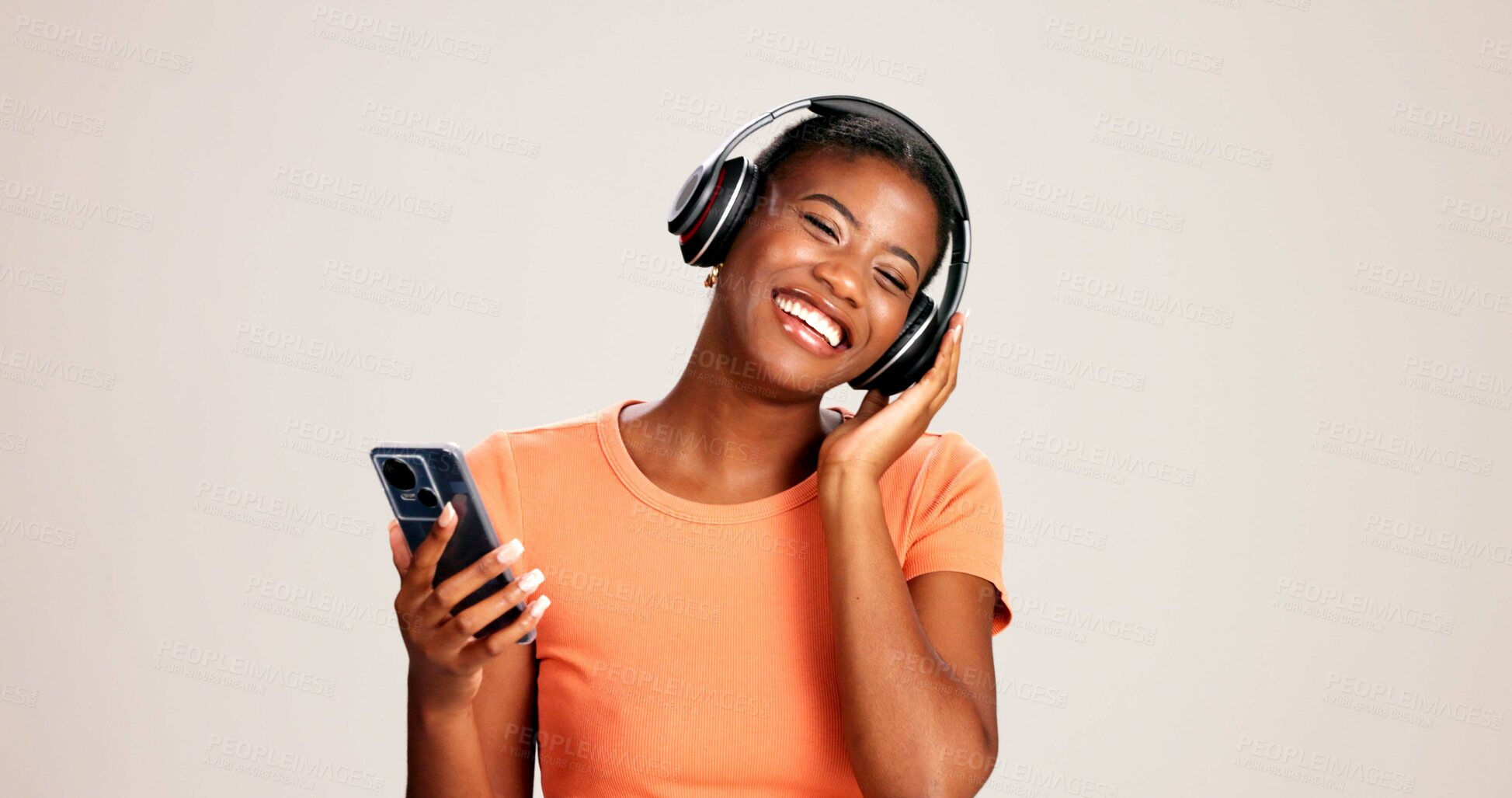 Buy stock photo Phone, woman and happy with headphones on studio background for podcast, listening to radio and enjoyment. Audio playlist, black person and excited with album, streaming subscription and mockup space