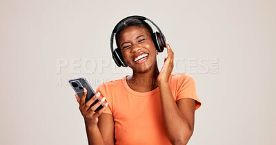 Buy stock photo Phone, woman and laughing with headphones on studio background for funny podcast, radio app and enjoyment. Audio playlist, black person and happy with music, online sound and streaming subscription