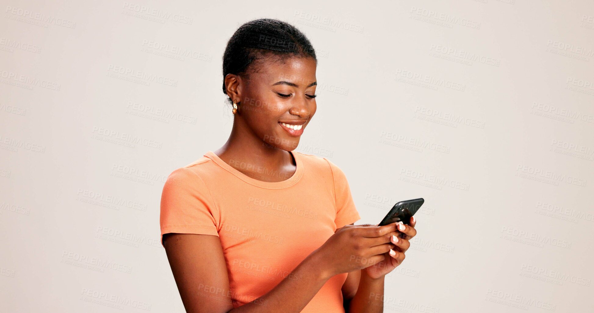 Buy stock photo Happy, black woman and typing with phone in studio for communication or social media on a white background. African female person or model with smile on mobile smartphone for online chat or texting