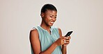 Happy, black woman and typing with phone in studio for communication or social media on a white background. African, female person or user with smile on mobile smartphone for online texting or app