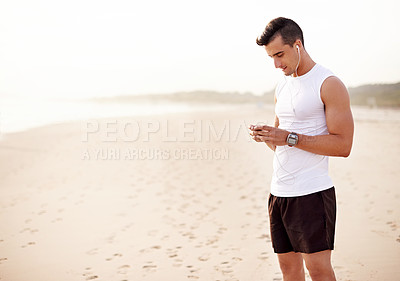 Buy stock photo Earphones, health and man by beach for fitness listening to music, podcast or radio for run. Outdoor, sport and male athlete with audio tech on sand for cardio workout, exercise or training playlist