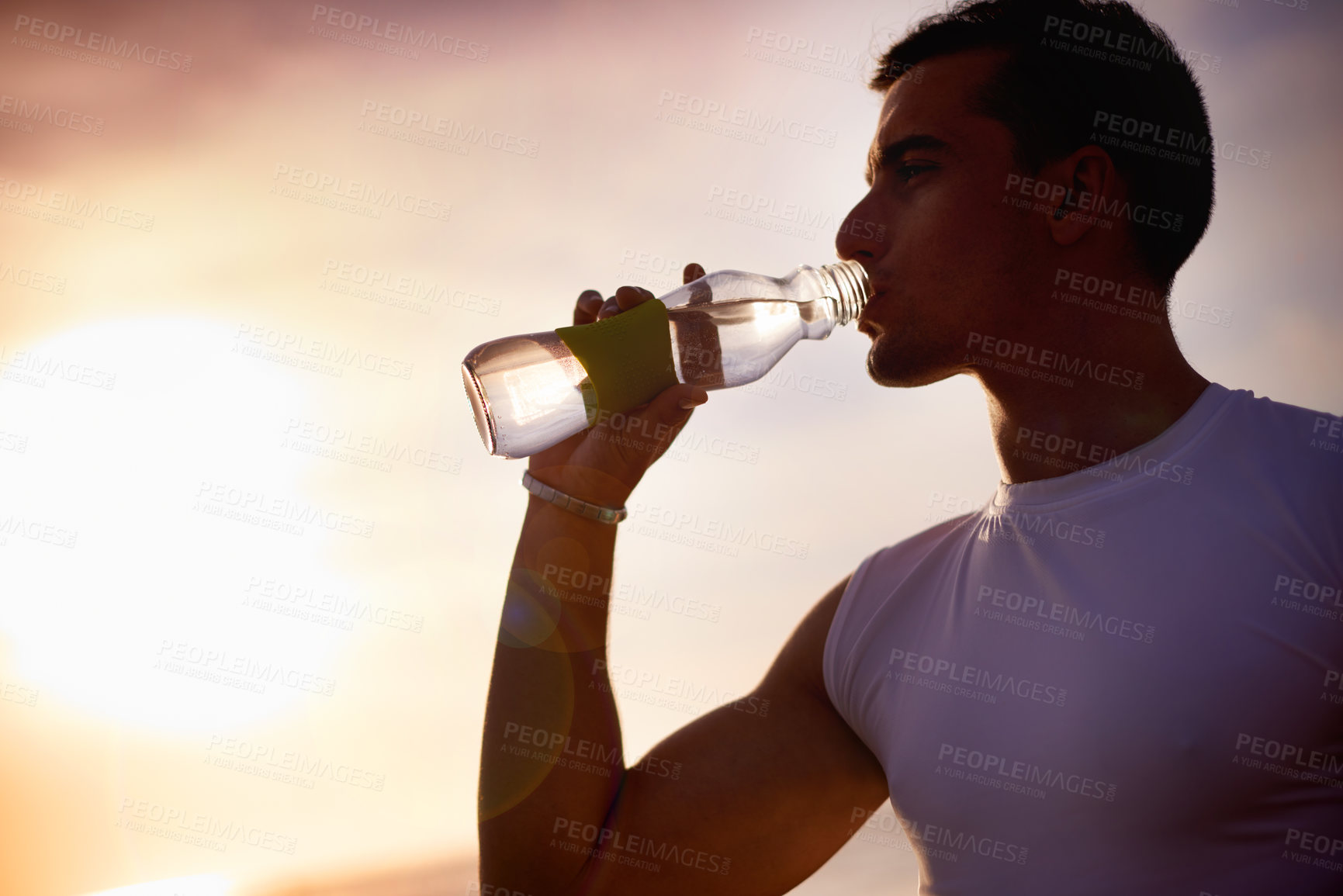 Buy stock photo Fitness, man and drinking water at beach at sunset for health, body wellness and relax on sports break. Outdoor, thirsty runner and bottle for hydration, electrolytes and liquid nutrition for diet