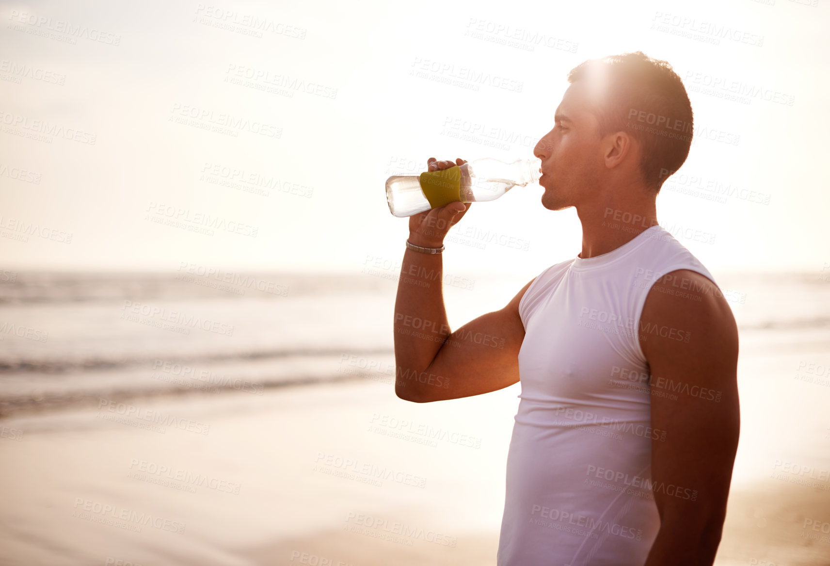 Buy stock photo Fitness, relax and man on beach with drink for hydration, outdoor workout and thinking with waves at sunrise. Water, bottle and runner at ocean with rest, mockup and calm morning exercise in nature