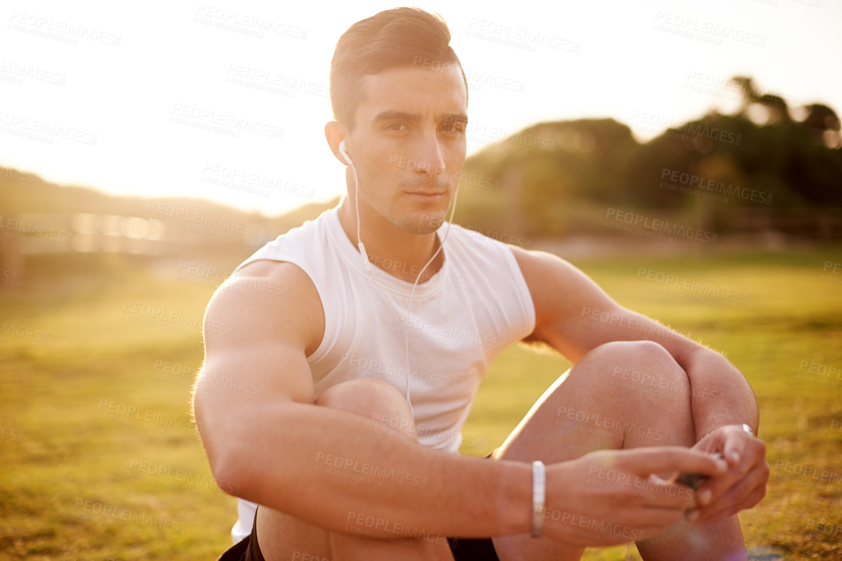 Buy stock photo Man, fitness portrait with headphones on grass for exercise, break and listening to music in nature. Serious, athlete and sunrise with tech for outdoor workout playlist, training and run in morning