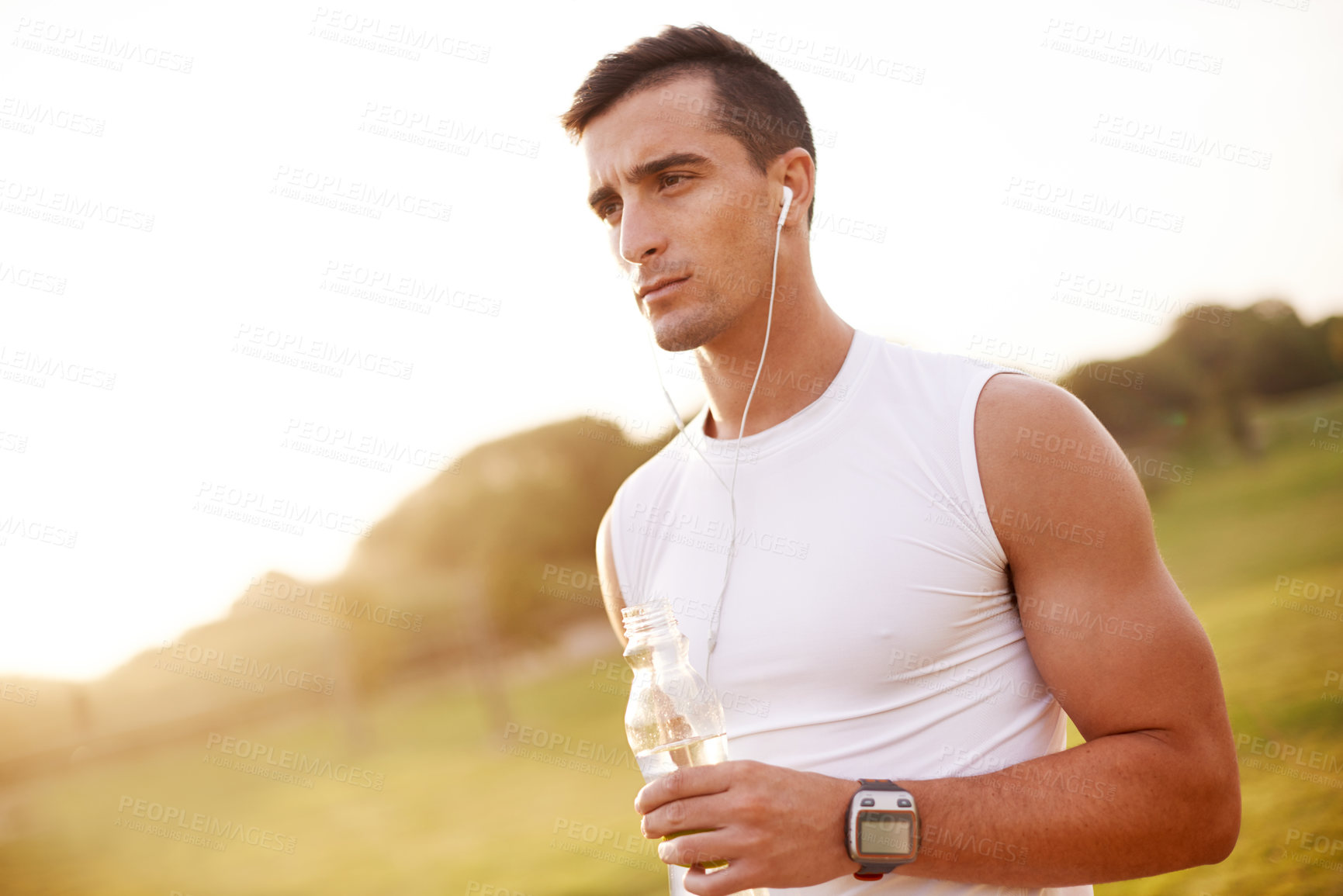 Buy stock photo Fitness music, man and water outdoor for health, body wellness and thinking on sports break. Earphones, thirsty runner and bottle for hydration, serious and listening to podcast at park at sunset