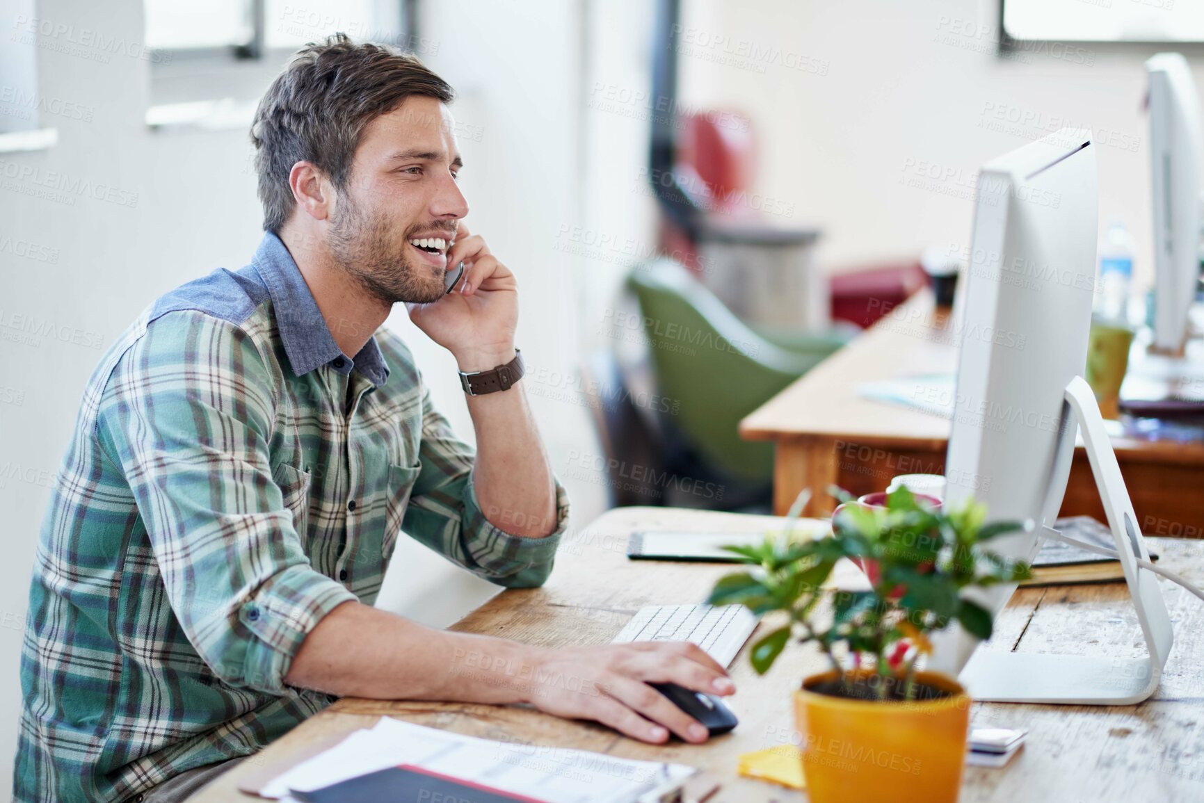 Buy stock photo Shot of a young designer talking on a cellphone while working on a computer