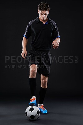 Buy stock photo Fitness, skill and football with man in studio for recreational sports training isolated on black background. Freestyle, control and young male athlete with talent in soccer kit with ball tricks 