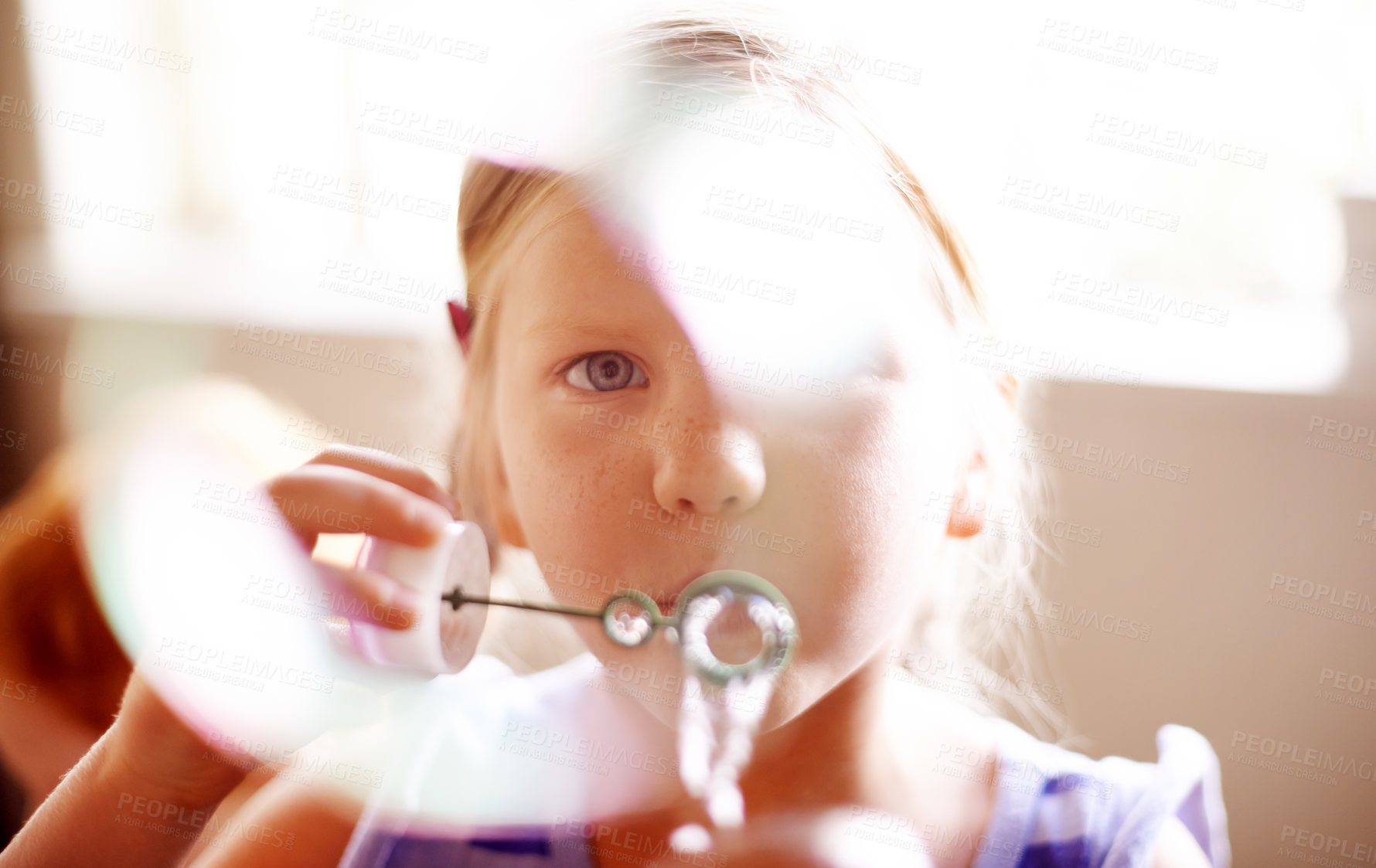 Buy stock photo Girl, kid and blowing bubbles in home for sensory stimulation, cognitive development and creative activity. Bokeh, person and wand with liquid soap for playing fun game, coordination and imagination