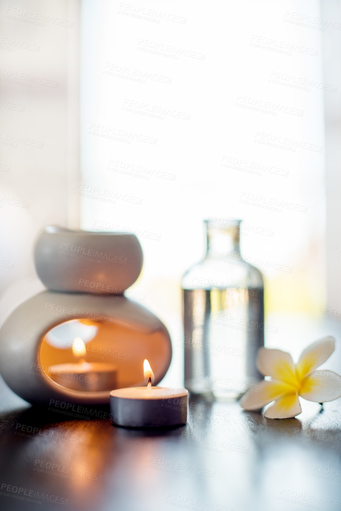 Buy stock photo Spa, luxury flower and essential oil with candles on table for wellness retreat, self care treatment or aromatherapy. Space, zen salon or empty room with tranquil display or natural products to relax
