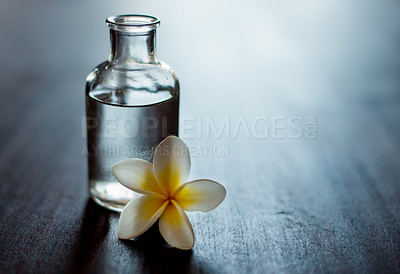 Buy stock photo Wellness, luxury and essential oil with flower on table for body moisturizer, stress relief and aromatherapy massage. Interior space, cosmetics and natural extract for skincare, antioxidants or relax
