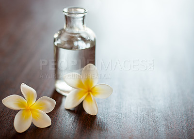 Buy stock photo Wellness, spa and essential oil with flowers on table for skin health, stress relief and aromatherapy massage. Interior space, cosmetics and beauty product for skincare, antioxidants and anti aging