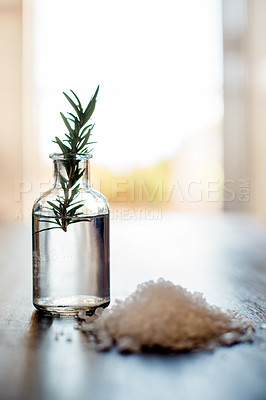 Buy stock photo Spa, body care and rosemary essential oil with salt on table for aromatherapy treatment, wellness or swedish massage. Interior space, health clinic and empty room with natural products for selfcare